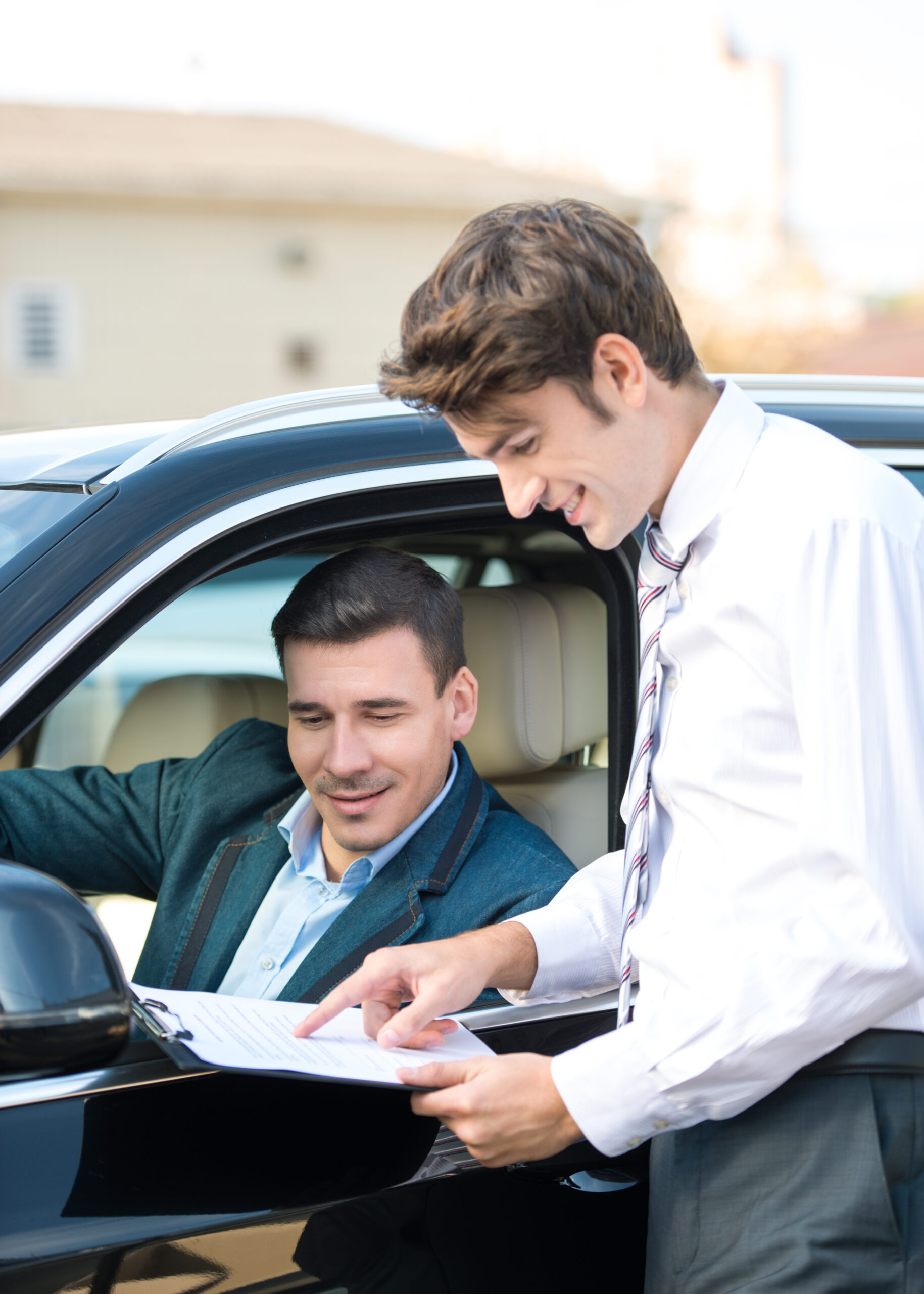 Zwei Männer diskutieren über Dokument im Auto.